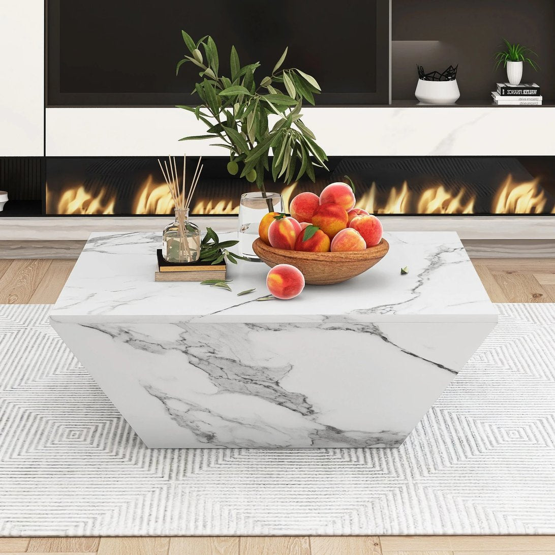 Table basse hexagonale effet marbre blanc TavovaT avec décoration élégante, bol de pêches et plante verte, cheminée design en arrière-plan