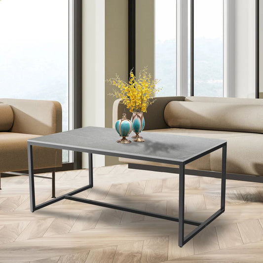 Table basse moderne TavovaT avec plateau gris effet béton et structure en métal noir, décorée de vases turquoise et fleurs jaunes dans un salon lumineux