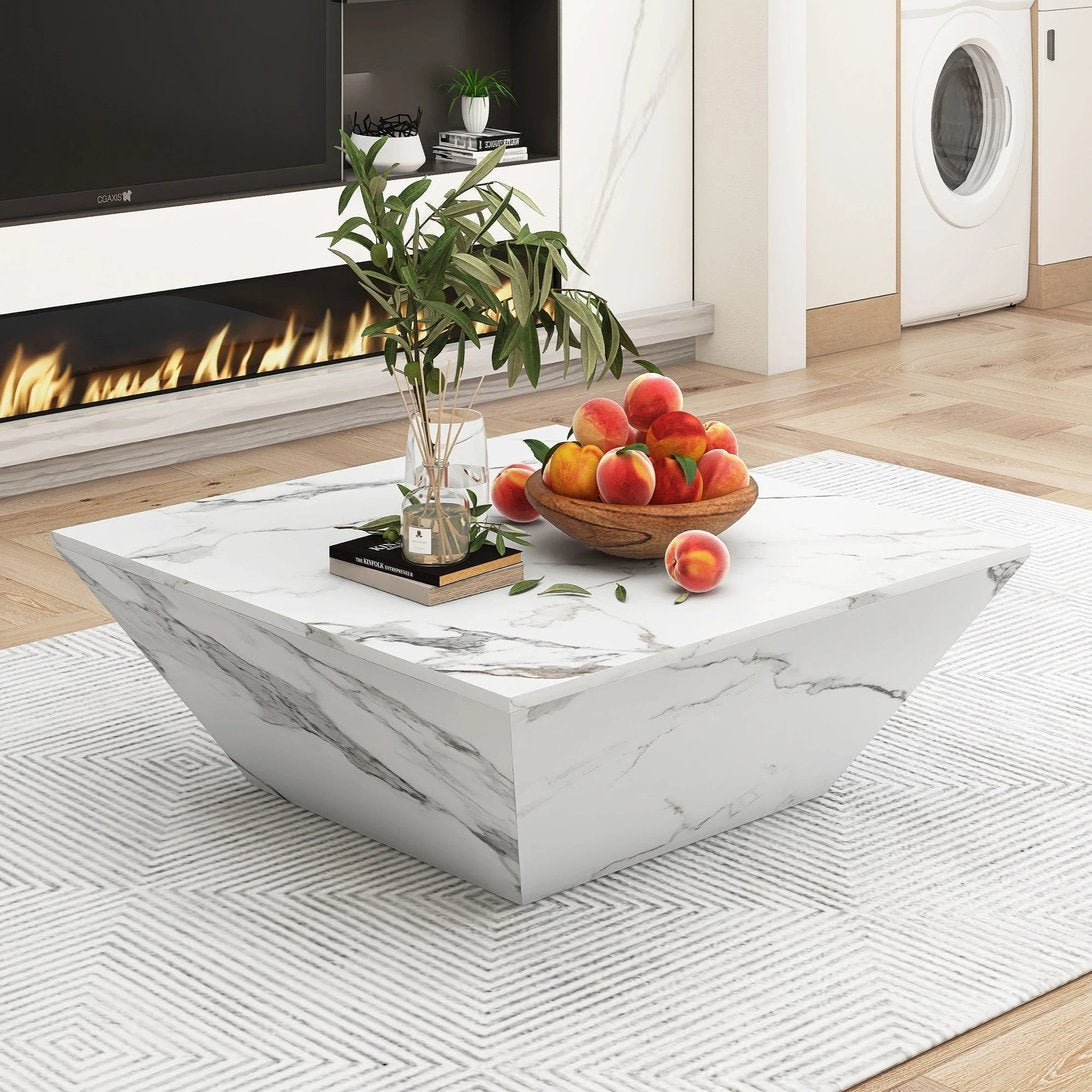 Table basse effet marbre blanc TavovaT au design géométrique moderne, placée sur tapis motif chevron, décorée de pêches et plantes